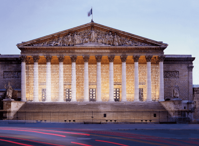 Une photo de l'assemblée nationale avec des 0 et des 1 superposés pour représenter le code de la République.